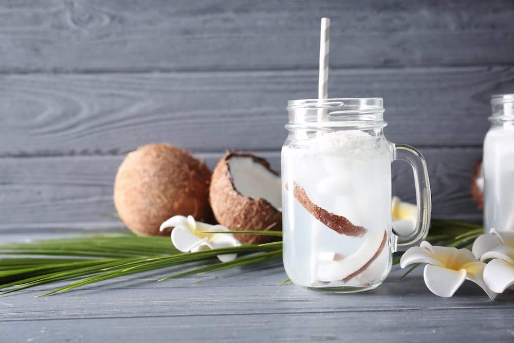 jars of coconut water in front of some opened coconuts